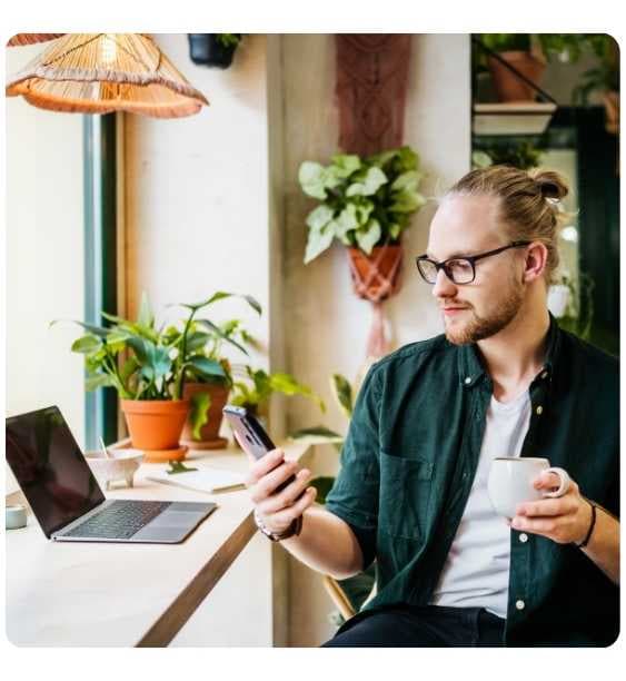 tanar blond verifica telefonul intr-o cafenea